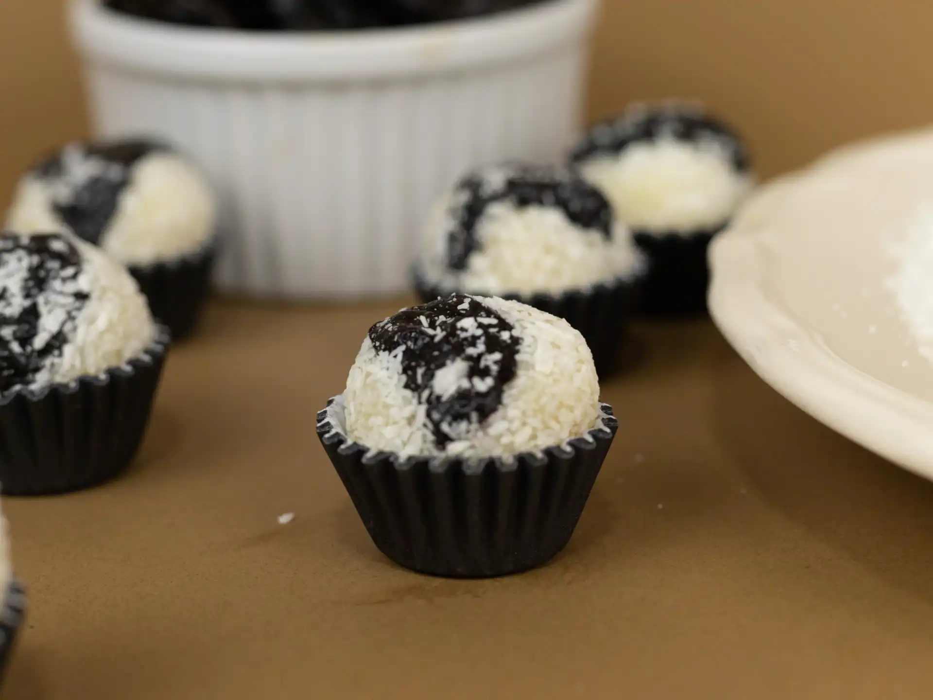 Olho de sogra, feito com massa de coco, leite condensado e ameixa, enrolado no coco ralado.